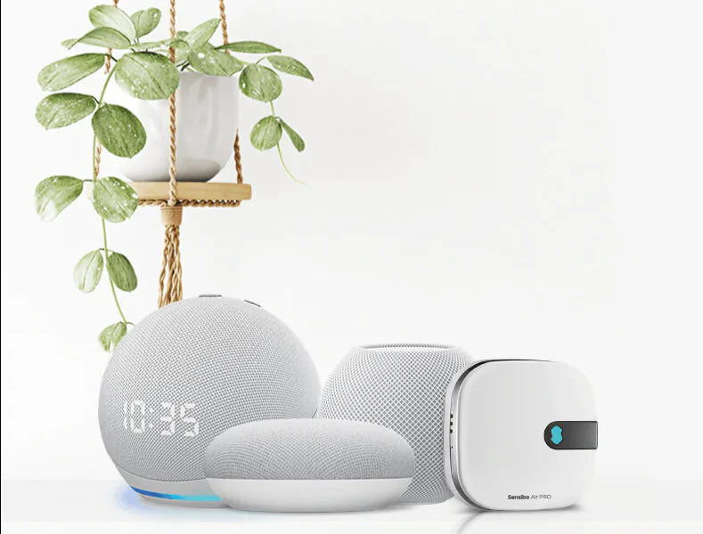 Smart home devices including a clock, speaker, and other gadgets on a white background with a plant.